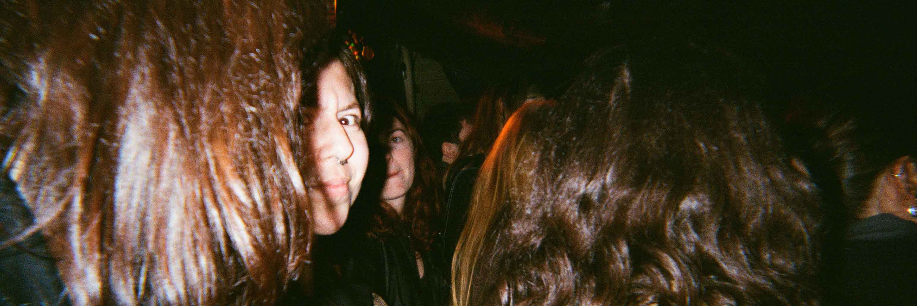 Maddy looking concerned at the camera standing in a crowd of people.