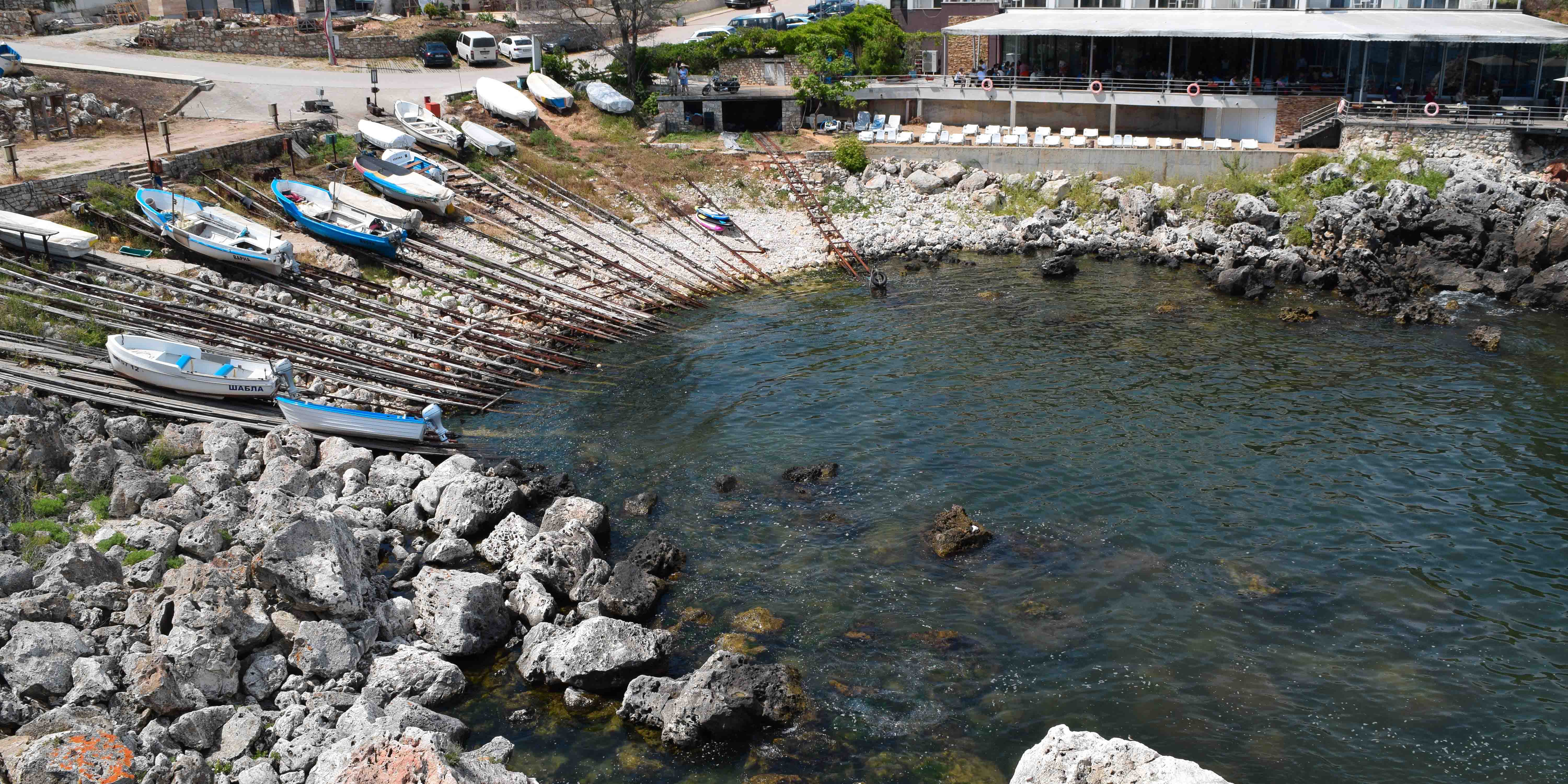 A launching pad for small boats into the water surrounded by small boats on rails.