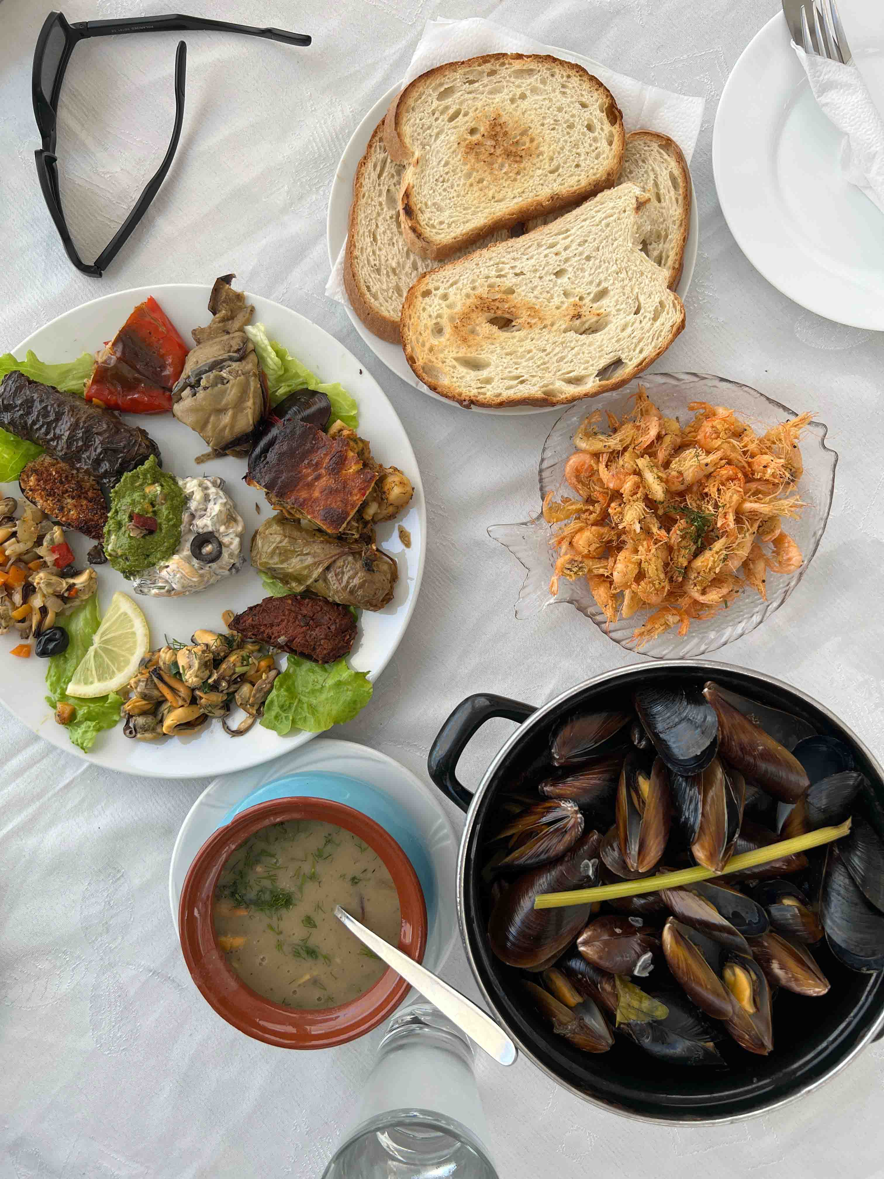 12 different dishes with mussels and a steamer of plain mussels.